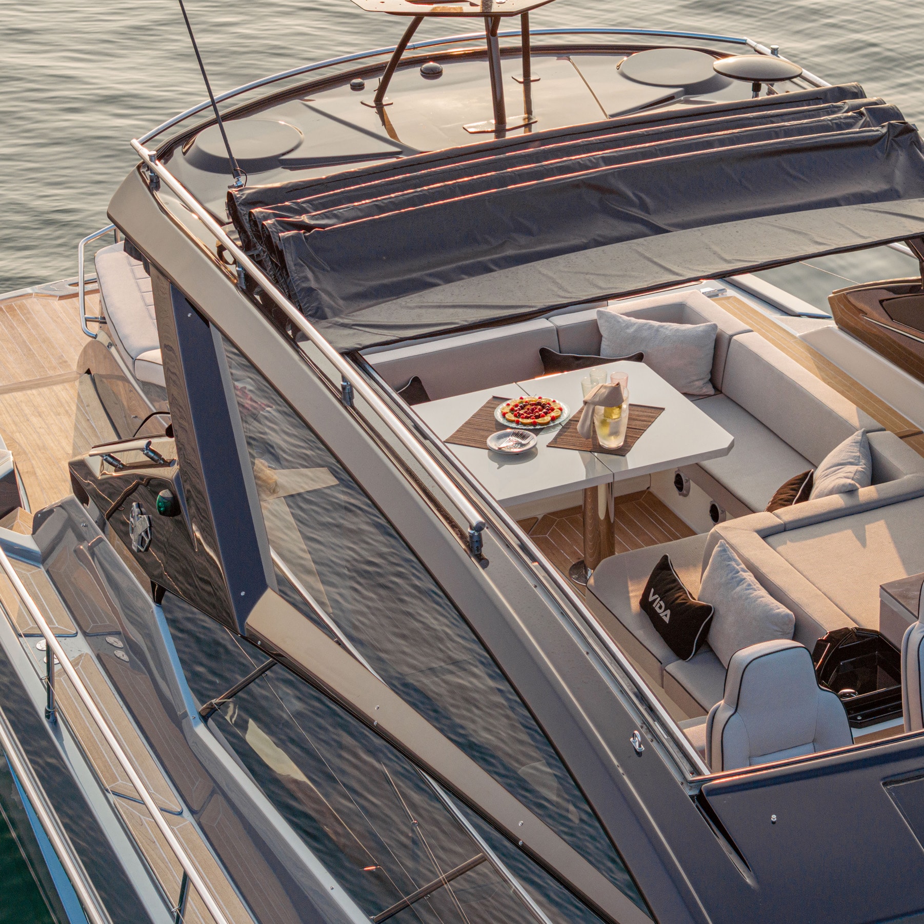 Vista dall’alto della terrazza di poppa con divanetti e tavolo apparecchiato per un aperitivo sul mare